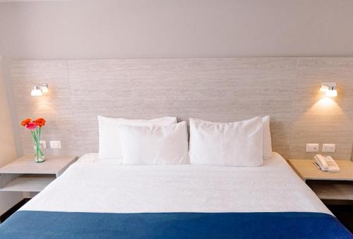 a bedroom with a large bed with white pillows and a phone at Kasa Hotel & Suites in Irapuato