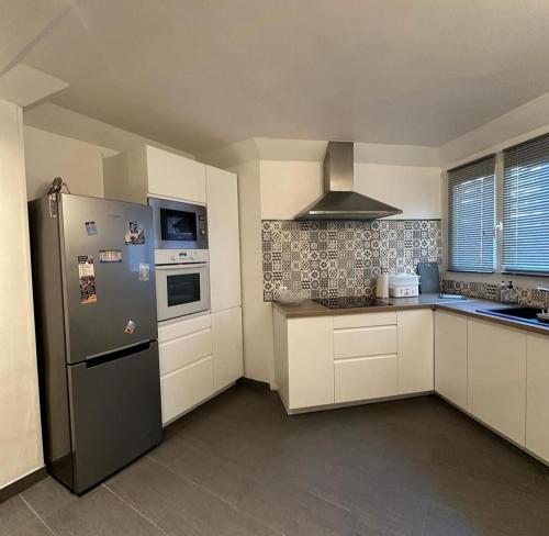 une cuisine avec un réfrigérateur en acier inoxydable et des armoires blanches dans l'établissement Casino Juan-les-pins, à Antibes