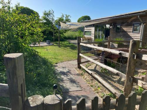 a fence next to a house with a goat at 't UijlenHuijs in Dussen