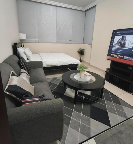 a living room with a couch and a tv at Regular Room - Shared Bathroom in Abu Dhabi