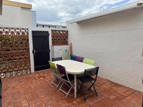 - une table et des chaises sur une terrasse avec un bâtiment dans l'établissement Pavillon cosy 6 pers Patio privé et plage à pied, à Port-la-Nouvelle