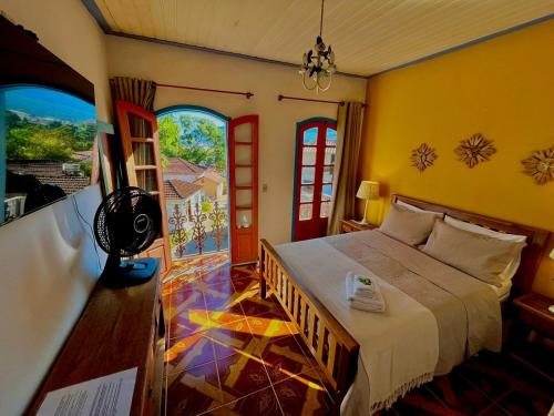 a bedroom with a bed in a room with windows at Pouso Antônio d'Maria in Tiradentes