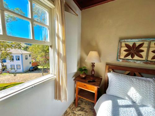 a bedroom with a bed next to a window at Pouso Antônio d'Maria in Tiradentes