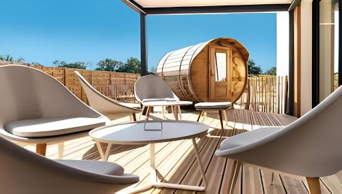une terrasse avec des chaises, une table circulaire et un tonneau dans l'établissement LE FAMYLISSE Séjour d'Exception Confort & Bien-Être en Lodge familial - 10min des Sables d'Olonne, à Sainte-Foy