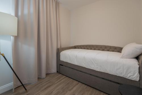 a bed in a room with a lamp and curtains at La Maison Kent - Par Aneyro in Quebec City