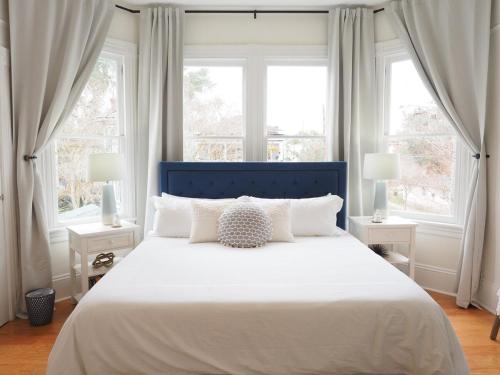 a bedroom with a large white bed with two windows at Stunning Forsyth Park Victorian - Walk to it all! in Savannah