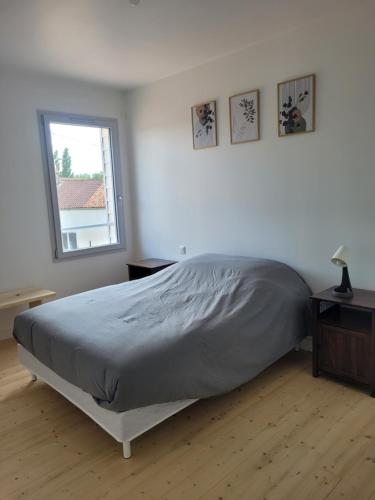 a white bedroom with a bed and a window at Les écuries in Secondigny