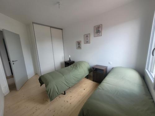 a bedroom with two green beds and a window at Les écuries in Secondigny