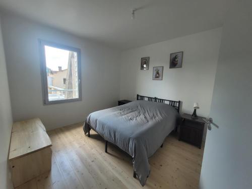 a white bedroom with a bed and a window at Les écuries in Secondigny