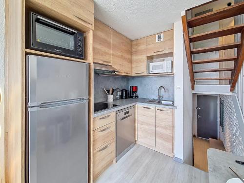 une cuisine avec un réfrigérateur en acier inoxydable et des armoires en bois dans l'établissement Appartement spacieux aux Menuires, 3 pièces, 8 pers, balcon Sud/Ouest, ascenseur - FR-1-344-1170, aux Menuires