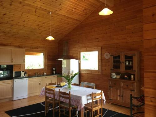 une cuisine avec une table et des chaises dans une pièce dans l'établissement Charmante maison en bois pour 5 personnes avec terrasse et jardin - FR-1-426-580, à Réaumur