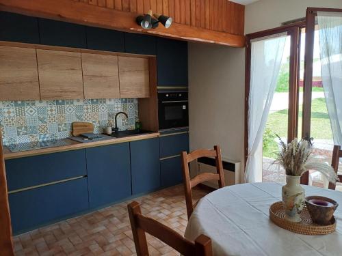 d'une cuisine avec des placards bleus et une table avec un vase. dans l'établissement Maison de campagne paisible avec vaste espace extérieur - FR-1-589-808, à Uzemain