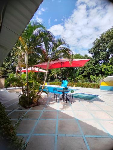 a table and chairs with a red umbrella next to a pool at Estancia Colibrí in Ricaurte