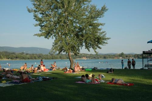 a group of people laying on the grass near a lake at Alabárdos Panzió és Apartmanház in Esztergom