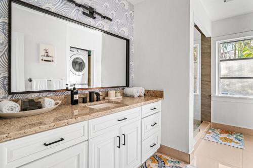 a bathroom with a sink and a large mirror at Poolside Getaway, Close To Dt Coastal Beach in West Palm Beach
