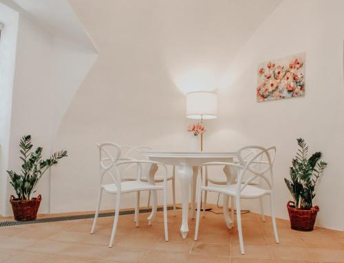 einen weißen Esstisch mit weißen Stühlen und einer Lampe in der Unterkunft Apartmán Baumgartner in Banská Štiavnica