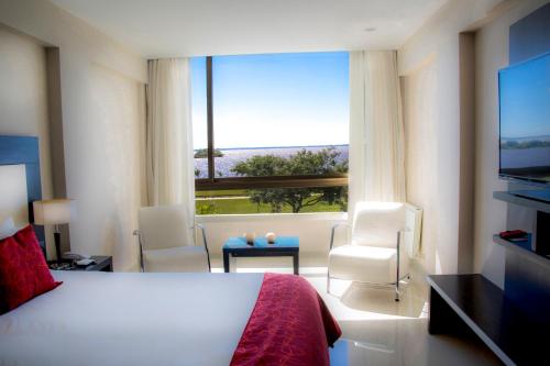 フェデラシオンにあるArena Resortのベッドと大きな窓が備わるホテルルームです。