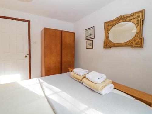 a bedroom with a bed with a mirror and towels at Wringford Farm Annexe in Torpoint