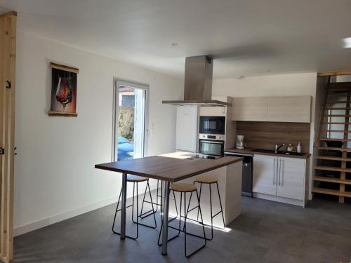 a kitchen with a wooden table and bar stools at Les écuries in Secondigny