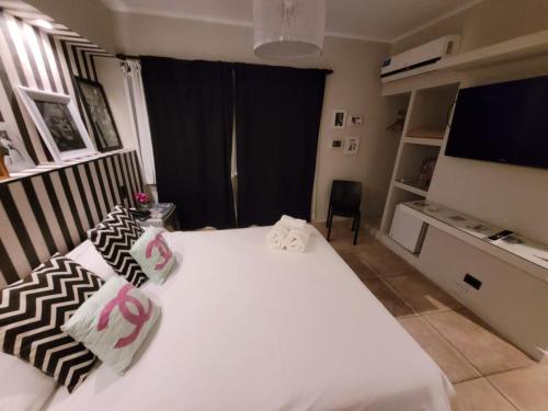 a bedroom with a white bed with pillows and a television at Santa Rosa Hotel in Olavarría