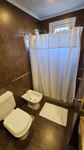 a bathroom with a toilet and a shower curtain at Santa Rosa Hotel in Olavarría