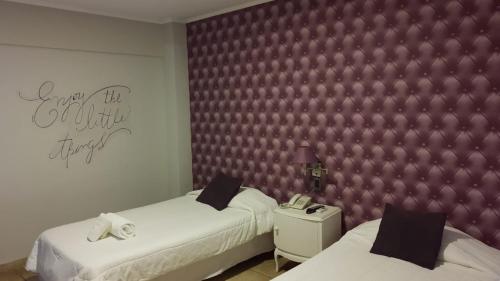 a bedroom with two beds and a purple wall at Santa Rosa Hotel in Olavarría
