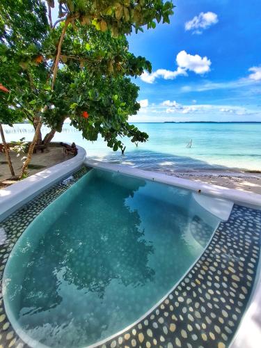 a swimming pool with a view of the beach at Villa Maayun, a nest in paradise in Letman