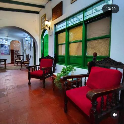 a living room with two red chairs and windows at Casa Paula acosta santa marta in Gaira