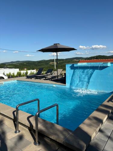 a swimming pool with stairs and an umbrella at Vikendica Oaza in Babići