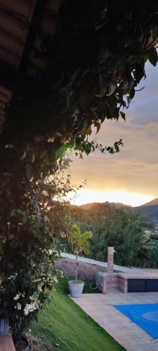 a view of a backyard with a bench and a tree at Chalé de alto padrão em condomínio in Santa Rita do Sapucaí