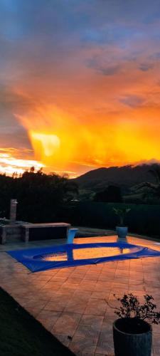 a sunset with the sun setting in the sky at Chalé de alto padrão em condomínio in Santa Rita do Sapucaí
