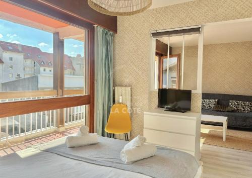- une chambre avec une télévision et une grande fenêtre dans l'établissement Appartement Mer & Soleil, à Le Touquet-Paris-Plage