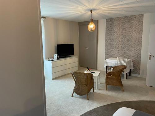 a living room with a television and a table with chairs at Le Tronçais in Saint-Bonnet-Tronçais