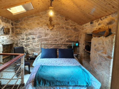 a bedroom with a bed in a stone room at A CASIÑA DA PALMERA in Vilar