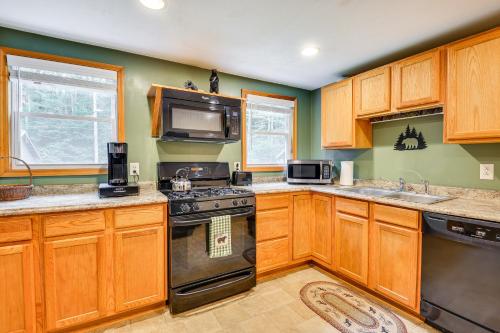 a kitchen with wooden cabinets and a stove and microwave at 1 Mi to Brantingham Lake New York Getaway! in Glenfield