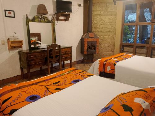 a bedroom with two beds and a dresser and a mirror at Hotel Hacienda Don Juan in San Cristóbal de Las Casas