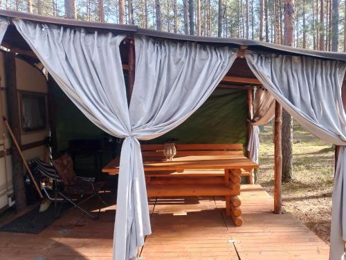 a tent with a wooden table in the woods at Zew Natury in Skorka