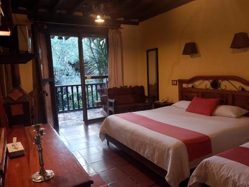 a bedroom with a bed and a sliding glass door at Hotel Hacienda Don Juan in San Cristóbal de Las Casas