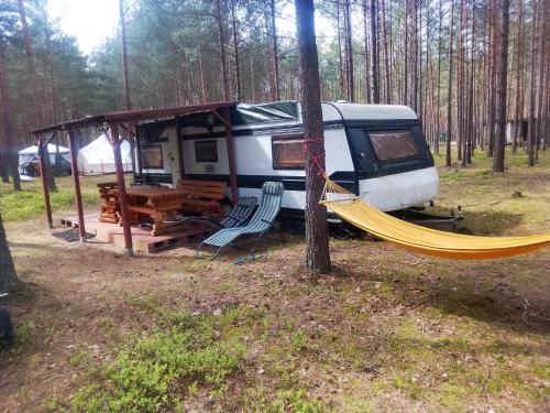 an rv with a hammock and a tent in the woods at Zew Natury in Skorka
