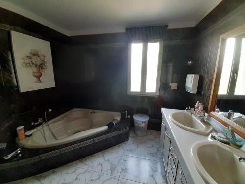 La salle de bains est pourvue d'une baignoire et de 2 lavabos. dans l'établissement Maison Malliague avec piscine chauffée, à Barjac