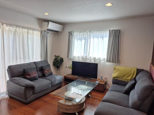 a living room with two couches and a tv at Cottage SORA in Onna