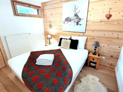 une chambre avec un lit blanc avec une couverture noire et rouge dans l'établissement Appartement 3* au centre des Gets, avec balcon-terrasse, Wifi, et garage - FR-1-598-137, aux Gets