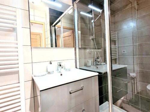 une salle de bain avec un lavabo et une douche avec un miroir dans l'établissement Appartement 3* au centre des Gets, avec balcon-terrasse, Wifi, et garage - FR-1-598-137, aux Gets