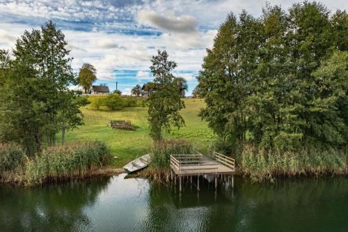 a dock in the middle of a lake with trees at Sodyba Po liepom in Krikštonys