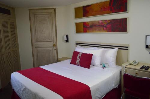 a bedroom with a large bed with red and white sheets at Hotel Century Reforma in Mexico City
