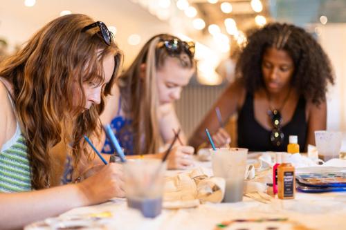 three girls sitting at a table writing on paper at YellowSquare Florence in Florence