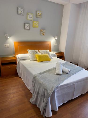 a bedroom with a large white bed with yellow pillows at Apartamento El Puerto III-Finisterre in Fisterra