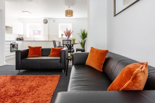 a living room with two black couches and orange pillows at Waterfront 2 Bed Apartment - Free Parking & Wi-Fi in Preston
