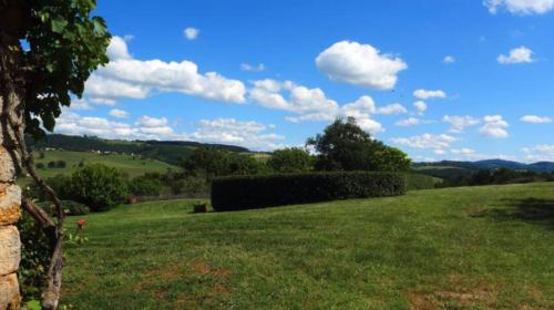 a field of green grass with a blue sky and clouds at Ferme de Jeanleix in Sauxillanges