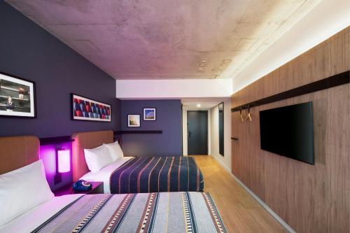 a hotel room with two beds and a flat screen tv at Moxy Montreal Downtown in Montréal